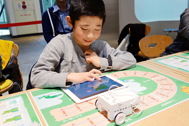ソニーの体験型科学館「ソニー・エクスプローラサイエンス」（東京・お台場）では、玩具としても教材としても楽しめるロボット・プログラミング学習キット「KOOV®」（クーブ）のワークショップを2019年5月11日（土）、12日（日）の2日間開催！子供たちは事前に組み立てられた「列車」を紙の線路に合わせ、「まっすぐ走ったあと、曲がる」「○○駅で止める」といった、モーターを制御する初歩的なプログラミングに挑戦します。
